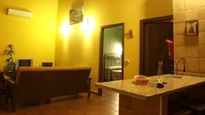 A room with a yellow wall, a wooden bench, a granite countertop, and a door leading to another room.