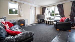 A living room with a fireplace, a sofa, a TV, and a window with curtains.