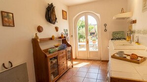 Une cuisine équipée d’une cuisinière, d’un plateau à café et d’une porte donnant sur un espace extérieur.