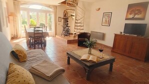 Un salon comprenant un canapé, une table basse, un téléviseur et un escalier en colimaçon.
