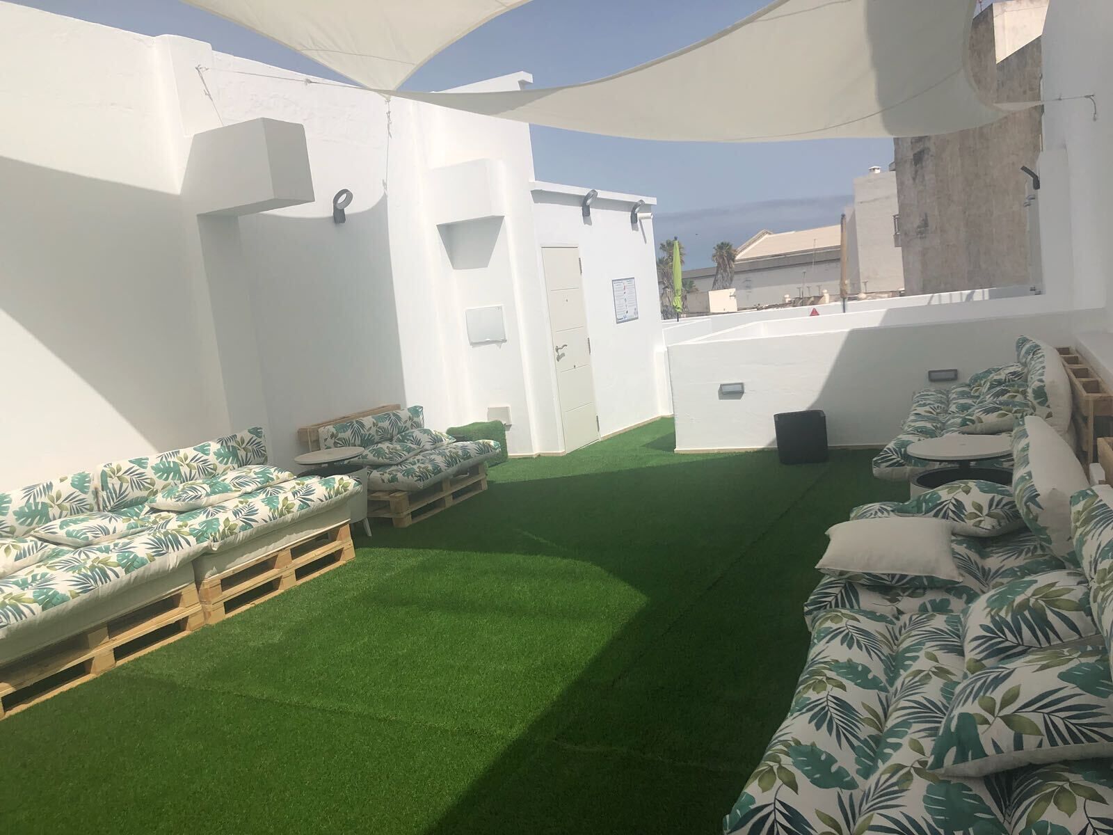 A rooftop terrace with green artificial turf, white walls, and a white ceiling.
