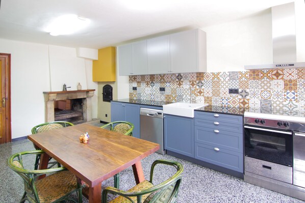 A kitchen with a wooden table, chairs, a dishwasher, and an oven. - Catalan farmhouse with pool and an incredible natural environment, for groups of 7 or 13 (Bescanó)