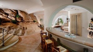 Un intérieur moderne avec un mur en pierre, un espace salon aux lignes courbes et un bar.