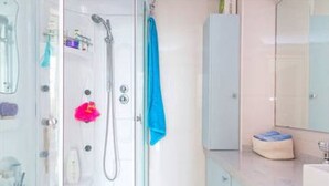 A bathroom with a glass shower enclosure, a white sink, and a mirror.