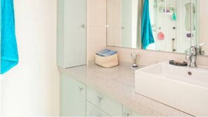 A bathroom with a large mirror, a sink, and a towel rack.