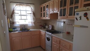 A kitchen with pink cabinets, a stove, a sink, and a refrigerator.