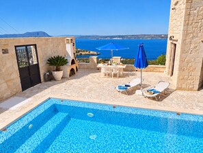A pool area with a view of the sea, stone walls, and outdoor furniture. - A charming 3 bedroom stone villa w/ privacy, private pool & fantastic sea views. (Chania)