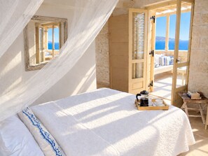 A bedroom with a bed, a coffee table, and a view of the sea. - A charming 3 bedroom stone villa w/ privacy, private pool & fantastic sea views. (Chania)