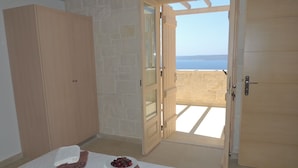 Une chambre à coucher avec un lit, une armoire et une porte ouverte donnant sur un balcon avec vue.