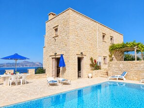 Un bâtiment en pierre doté d’une piscine, d’un espace extérieur aménagé et offrant une vue sur la mer.