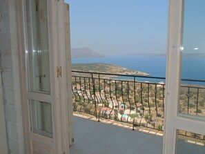 A balcony with a view of a coastal landscape, including a body of water and distant hills. - A charming 3 bedroom stone villa w/ privacy, private pool & fantastic sea views. (Chania)