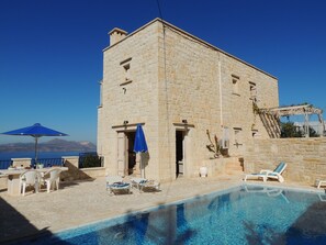 A stone building with a pool, lounge chairs, and a view of the sea. - A charming 3 bedroom stone villa w/ privacy, private pool & fantastic sea views. (Chania)