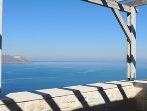 A coastal view with a clear sky, a stone wall, and a wooden structure. - A charming 3 bedroom stone villa w/ privacy, private pool & fantastic sea views. (Chania)