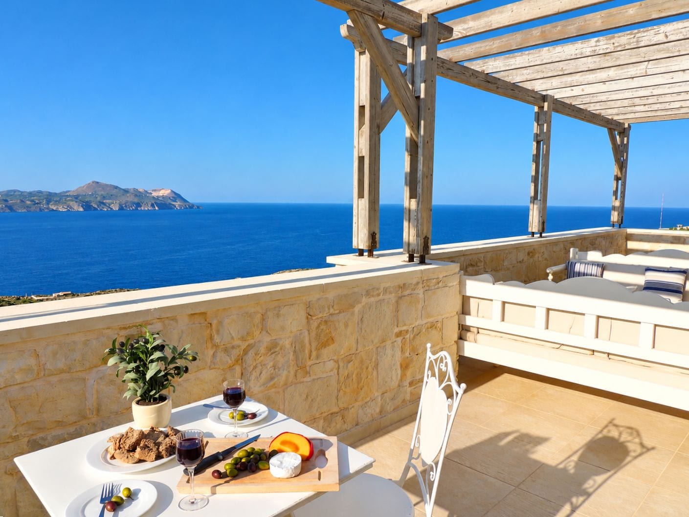 A terrace with a table set for a meal, overlooking the sea.