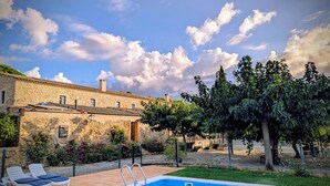 A stone building with a swimming pool, surrounded by greenery and a clear sky. - Rural house for groups and hikers, nature and tranquility lovers. (La Torre Vella)