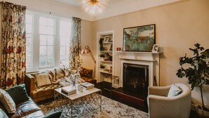 Un salon chaleureux avec une cheminée, un canapé, une table basse et une bibliothèque.