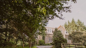 Un sentier menant à un bâtiment traditionnel en pierre, entouré d’une végétation luxuriante.