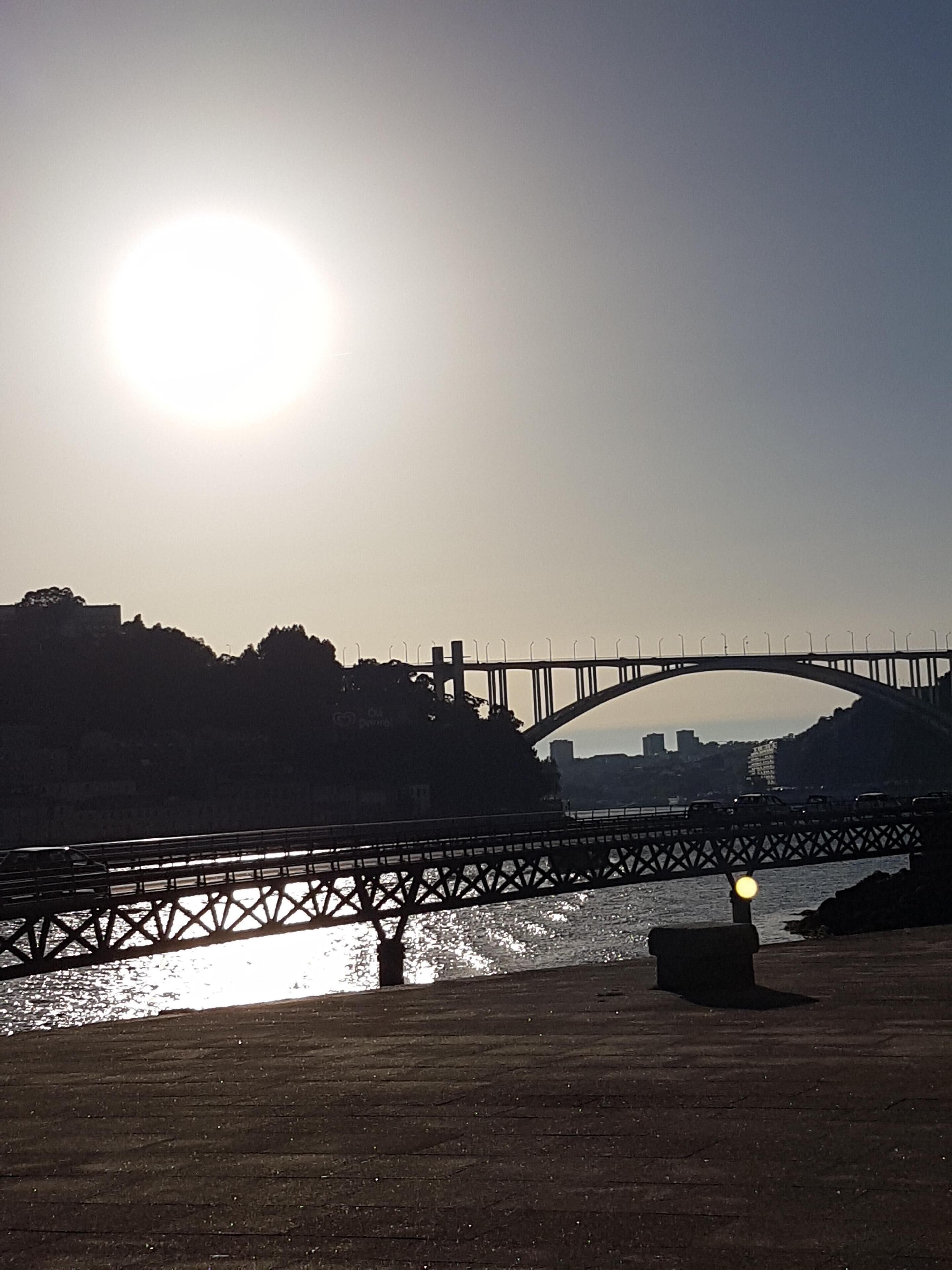 Un ponte sull'acqua con il sole sullo sfondo.