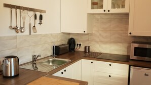 A modern kitchen with white cabinets, a stainless steel kettle, a toaster, and a microwave. - Cortijo el Chenil rural retreat, La Perrita (Casarabonela)