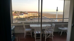Un balcón con vista a la playa y un edificio al otro lado de la calle.