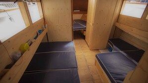 Ein kompakter Raum mit zwei Etagenbetten, Holzwänden und einem kleinen Fenster.