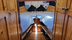 Ein gemütliches Blockhaus mit zwei Etagenbetten, Holzwänden und einem kleinen Tisch mit einem Buch.