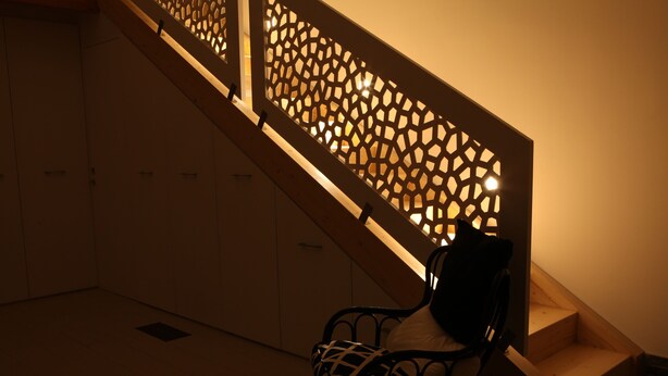A staircase with a wooden railing and a bench at the bottom.