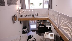 A compact, multi-level apartment with a kitchen, dining area, and a balcony with a view.