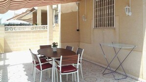 Une terrasse avec une table et des chaises, une petite table et un auvent décoratif.