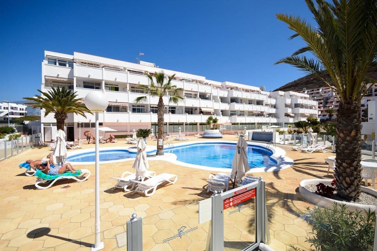 Ein Hotel mit Pool, Liegestühlen und Palmen.