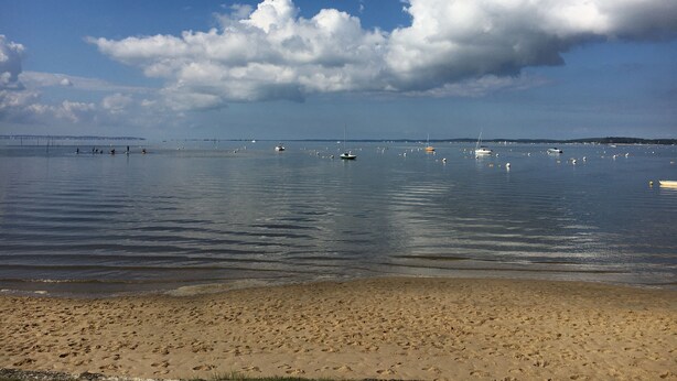 A beach with calm waters, boats, and a distant bridge. - Very nice and cozy house 10 minutes from the Bassin   (Arès)