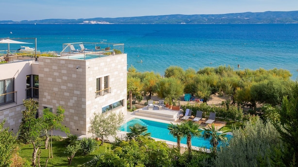 A modern building with a rooftop pool overlooking a clear blue sea.