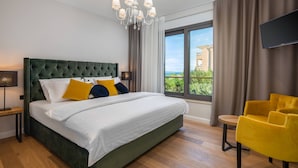 A modern hotel room with a large bed, a view of the outdoors, a flat-screen TV, and a yellow armchair.