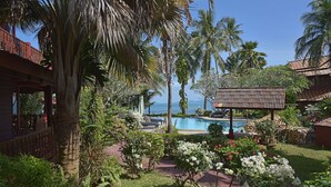 A pool area with a view of the sea, surrounded by lush greenery and palm trees. - Amazing 3 Bedroom, Thai Style Beachside, Villa (Koh Samui)