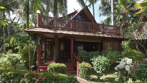 A traditional wooden house with a porch, surrounded by lush tropical vegetation. - Amazing 3 Bedroom, Thai Style Beachside, Villa (Koh Samui)