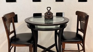 A round glass table with a dark wooden frame, two dark wooden chairs, and a heart-shaped object on the table. - Room in the heart of Cancun (29)