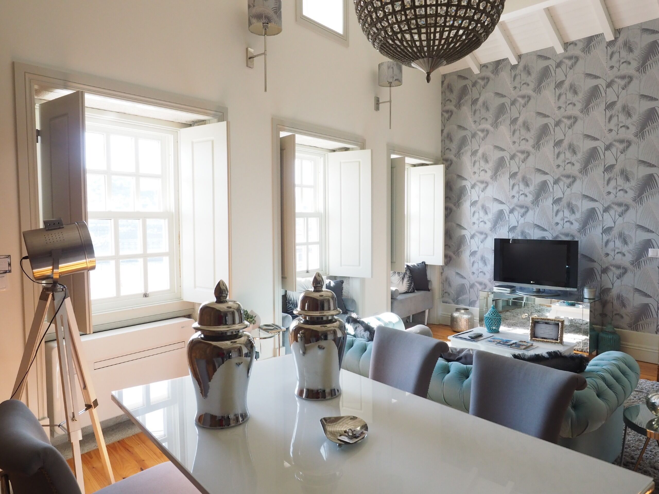 A modern living room with a large window, a dining table, and a television.