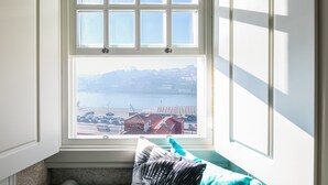 A room with a bay window overlooking a waterfront view, including a dock and buildings. - Oporto Platinum Loft // Luxury Accommodation// Unforgettable Douro River View. (Porto)