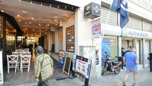 Straßenansicht mit einem Restaurant, einem Schild für 'LAVAZZA' und einem abgestellten Motorrad.