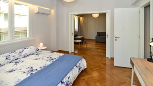 Ein Schlafzimmer mit Bett, Nachttischlampe und Blick auf einen Essbereich.