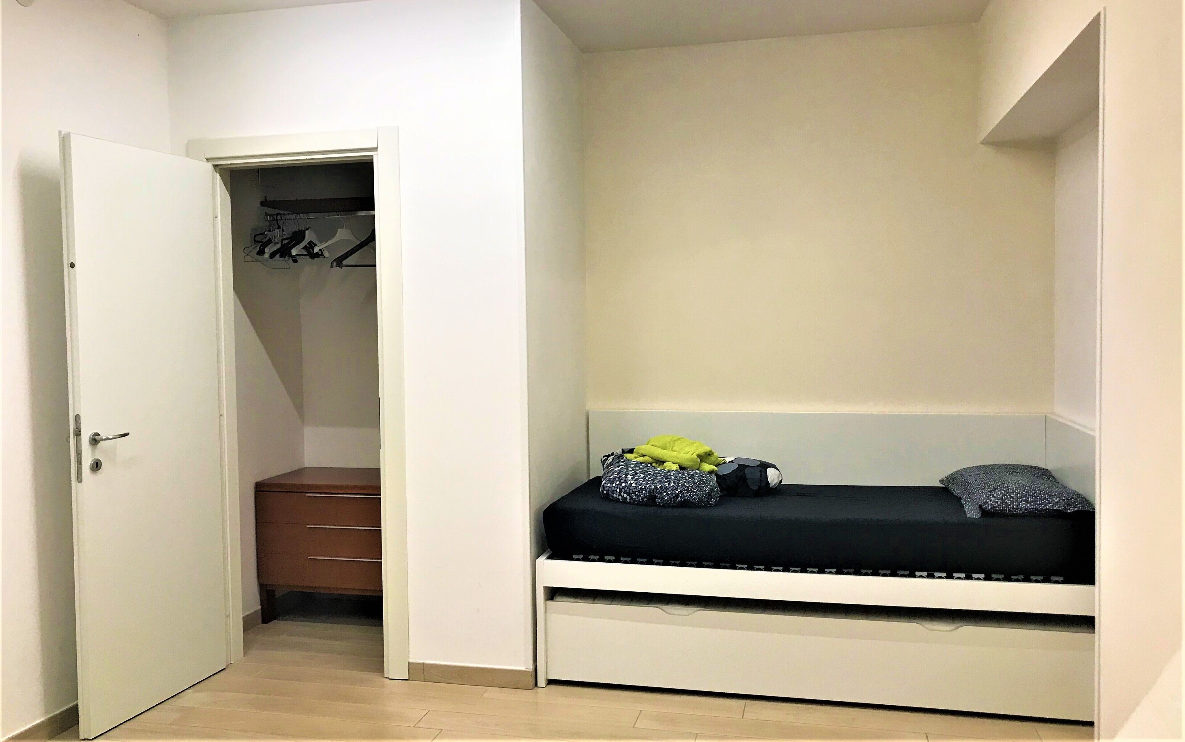 A small room with a bed, a closet, and a wooden cabinet.