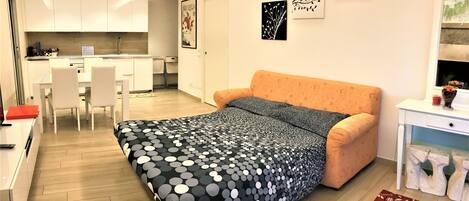 A compact living space with a kitchenette, a sofa bed, a dining area, and artwork on the walls.