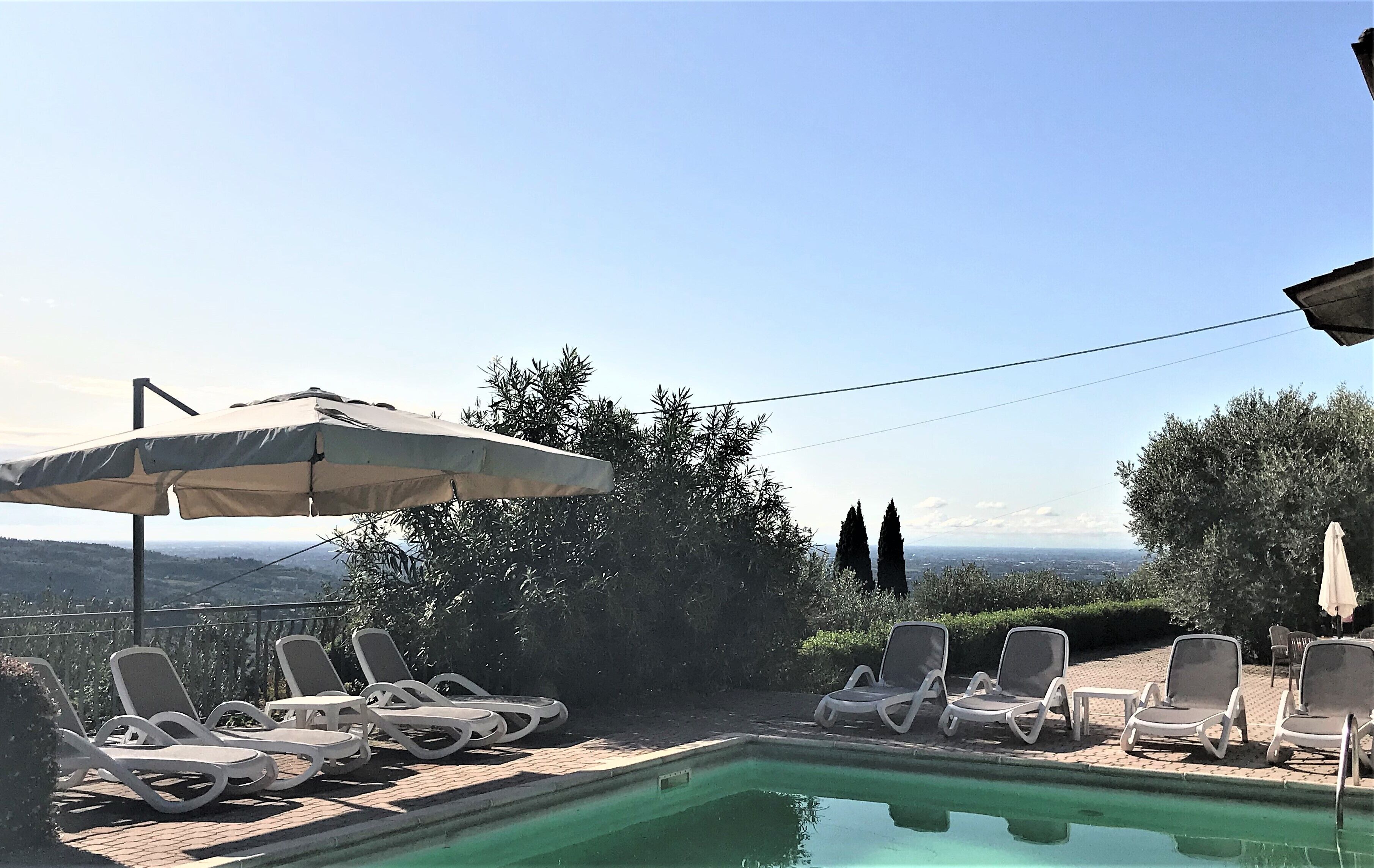 Una piscina al aire libre, sombrillas, sillones reclinables de piscina