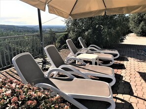 Una piscina al aire libre, sombrillas, sillones reclinables de piscina