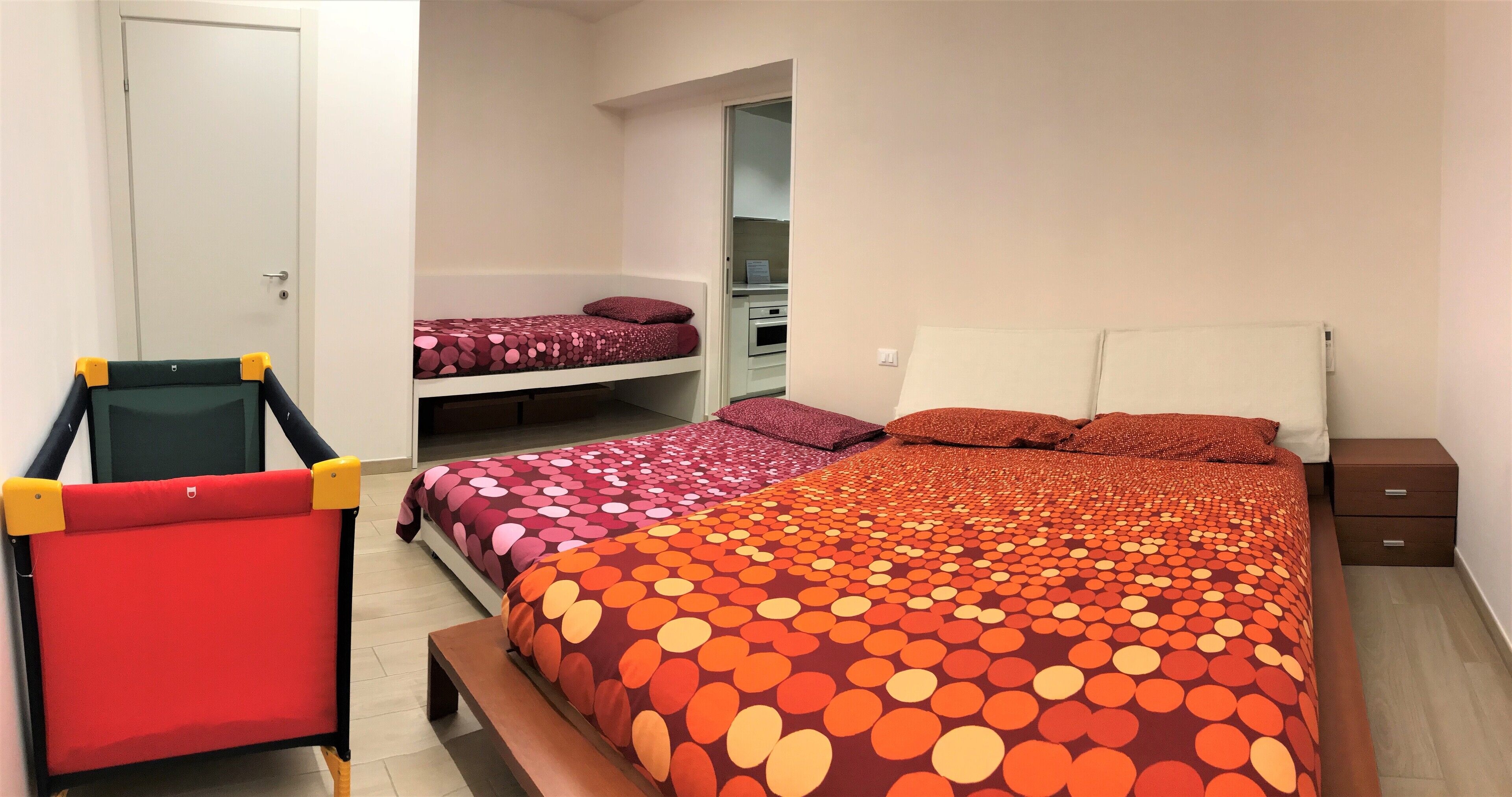 A bedroom with two beds, a bench, a chair, and a wardrobe.
