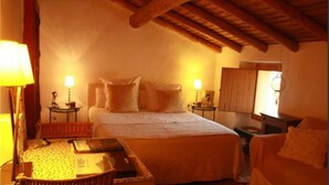 A cozy bedroom with a large bed, two bedside tables with lamps, a small table with a lamp, and a chair. - Country House with Swimming Pool Large Terrace and an amazing panoramic view (Marvão)