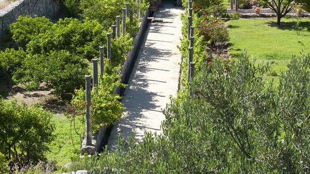 A coastal pathway leading to a stone archway, surrounded by lush greenery and overlooking a calm sea. - Room 5 a/c park view Beach&Sea front Castle parking (Zaton)