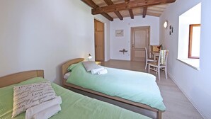 A bedroom with two beds, wooden beams on the ceiling, a small table with chairs, and a window providing natural light. - Room 5 a/c park view Beach&Sea front Castle parking (Zaton)