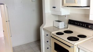 A compact kitchen with a white stove, a microwave, and a toaster. - Spacious 2 Bed 2 Bath Condo Across From The Beach (CHRIST CHURCH)