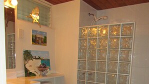 A bathroom with a toilet, a sink, and a shower with frosted glass panels. - Spacious 2 Bed 2 Bath Condo Across From The Beach (CHRIST CHURCH)